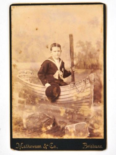 Photograph of Boy Sailor in Boat | Period: c1920 | Make: Mathewson & Co, Brisbane | Material: Sepia photograph on board.